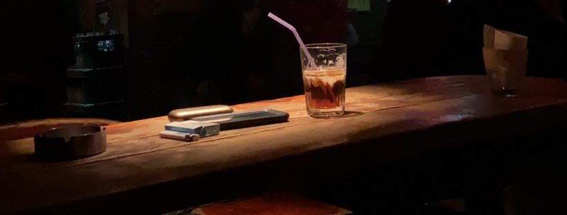 a mixed drink sitting on the counter in an empty bar