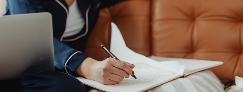 hand holding a black pen writing on a notebook