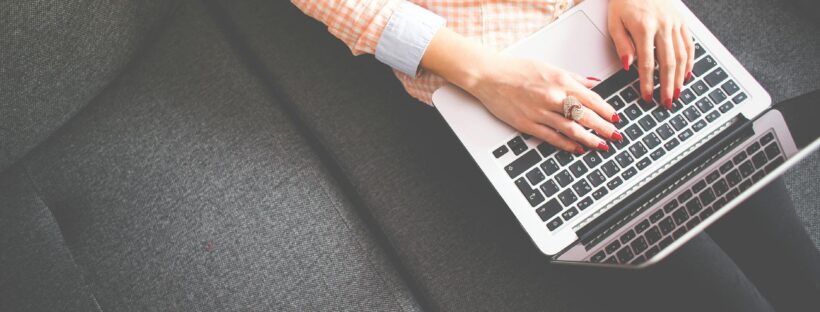 person sitting on gray sofa while using macbook